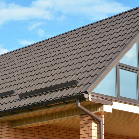 Building Modern House Construction with metal roof, rain gutter system and roof protection from snow board, snow bar (Snow guard). Roof Snow Guards: Building Materials & Supplies